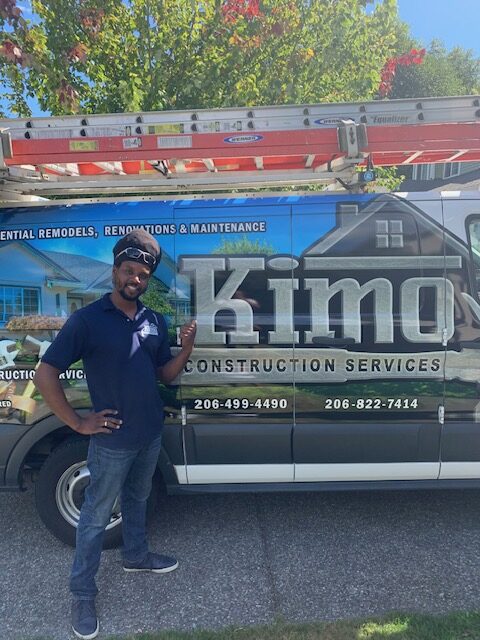 worker on front of a van with the kimo logo on it on a parking